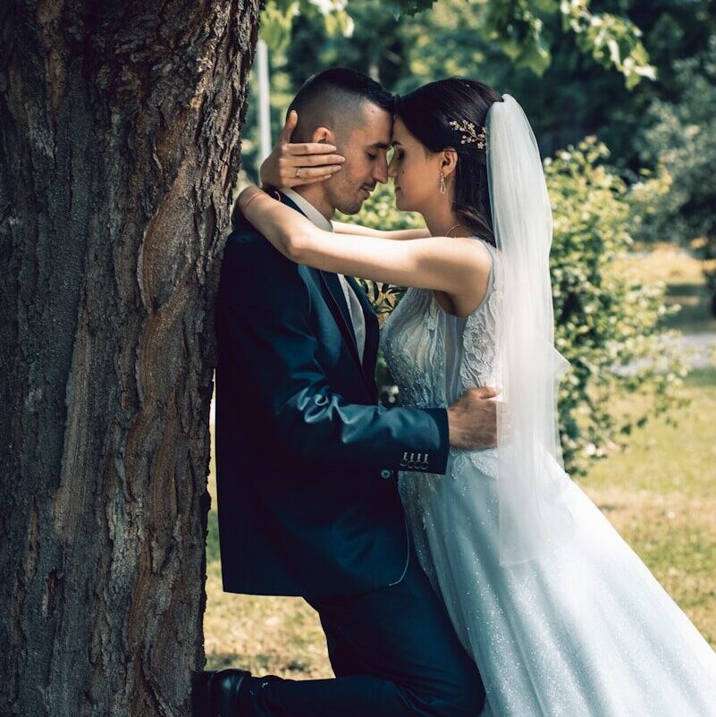 man and woman kissing beside brown tree during daytime